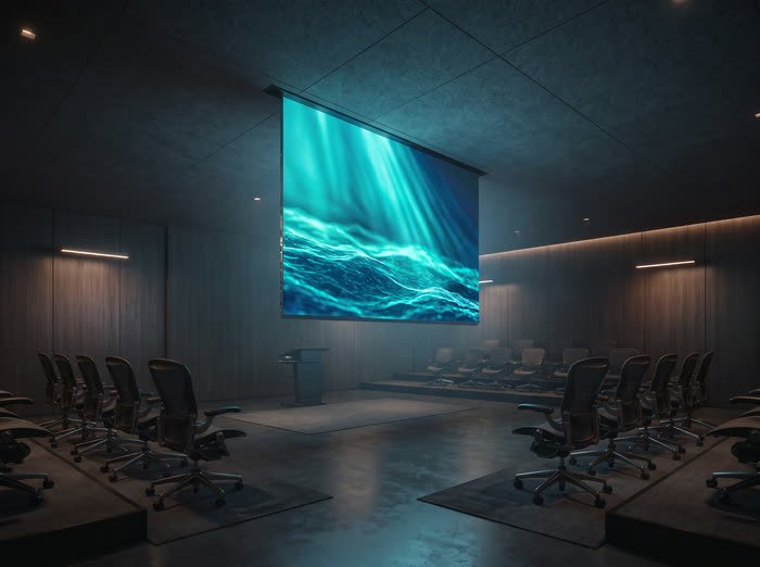 Flexible LED screen captured mid-deployment, unrolling from a recessed ceiling slot in a training room